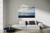 Blue Salton Sea layered photography print in a white floater frame, displayed above a light gray sofa in a modern living room